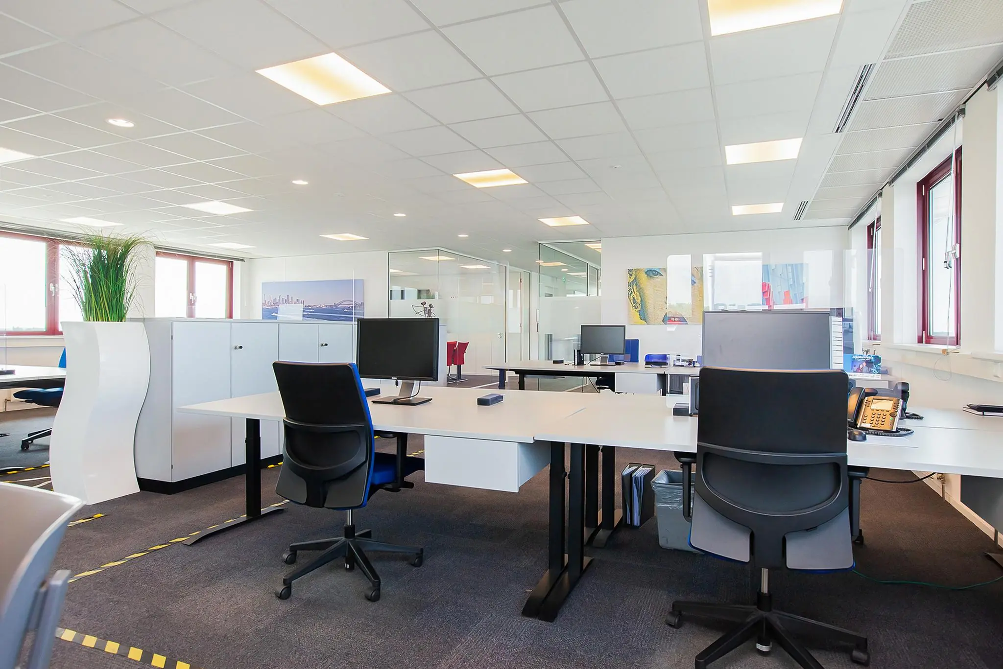 Modern en licht open kantoorpand aan de Laan der Verenigde Naties met werkplekken, bureaustoelen en computers.